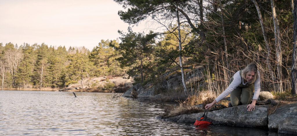 Lina ligger ner och skopar upp vatten ur sjön